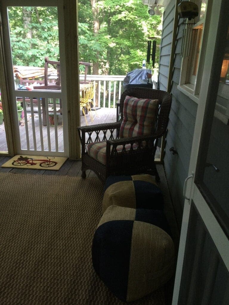 Screened porch with wicker furniture overlooking wooded lot